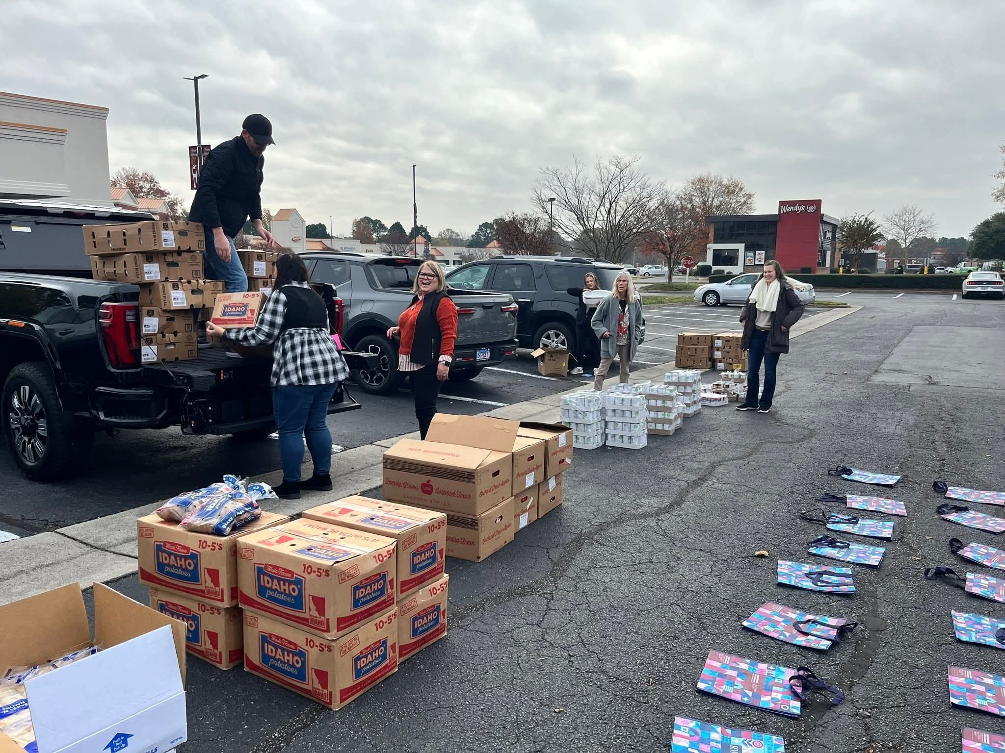 Boxes and bags of Thanksgiving food staged in a parking lot