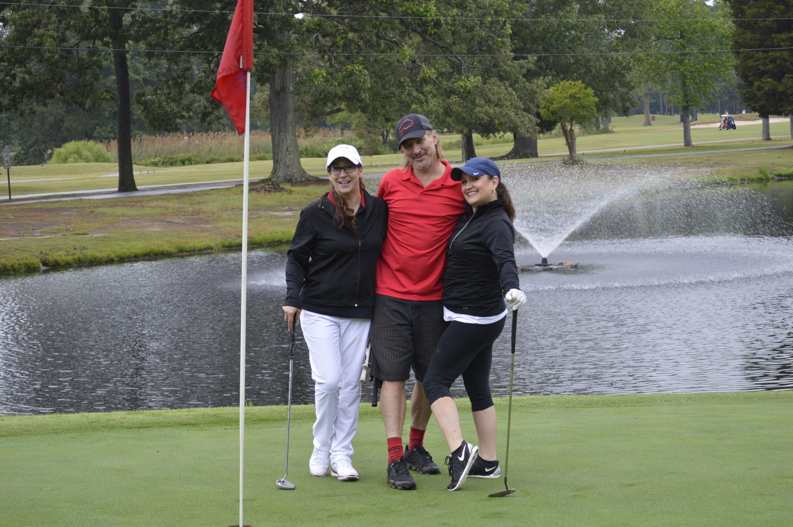 Golfers posing by a pond on the course