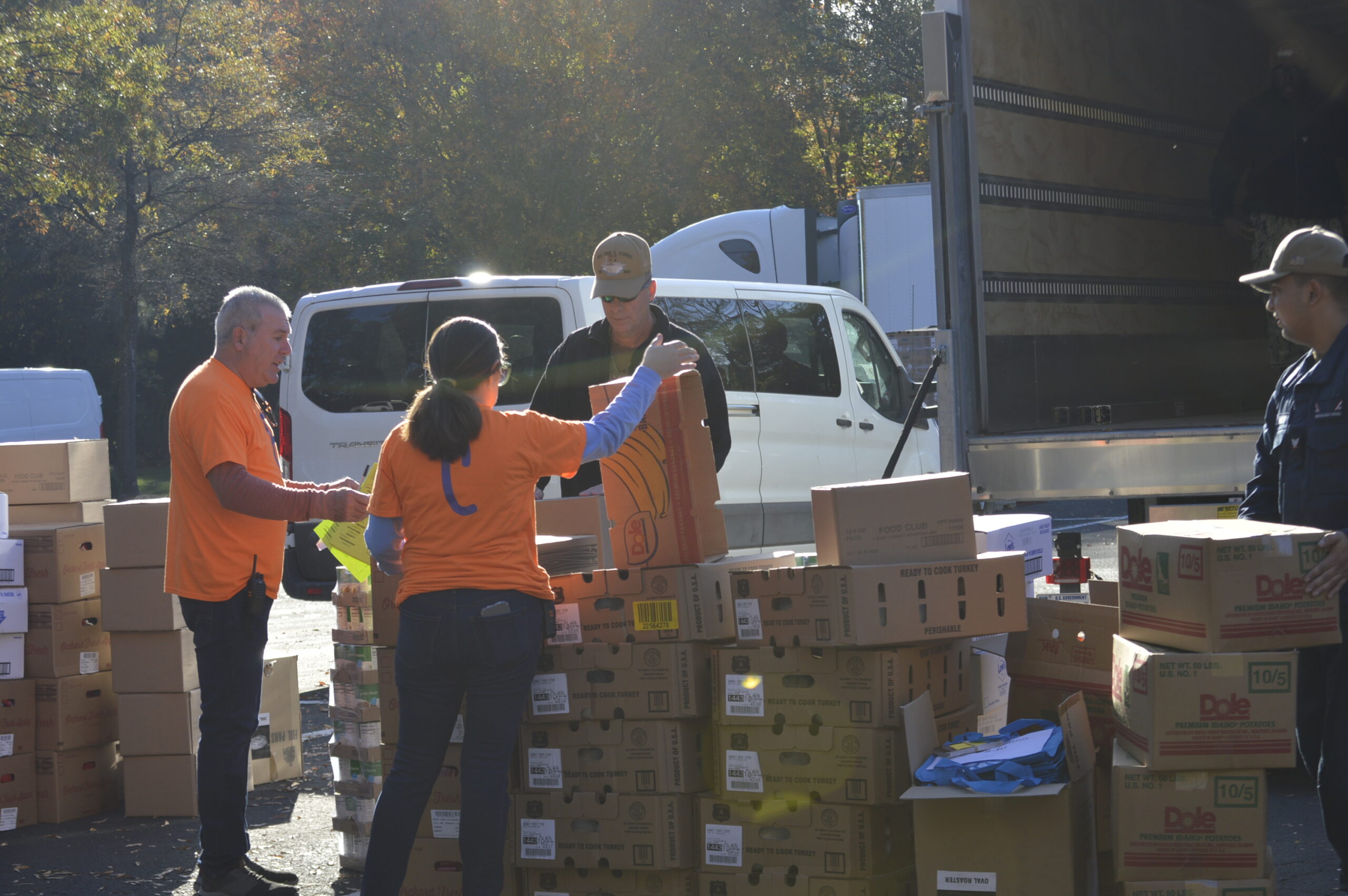Volunteers in orange shirts sorting boxes of donated food