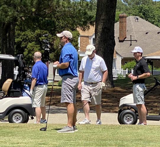 Golfers gathered near golf carts at the RW Towne Foundation Golf Tournament