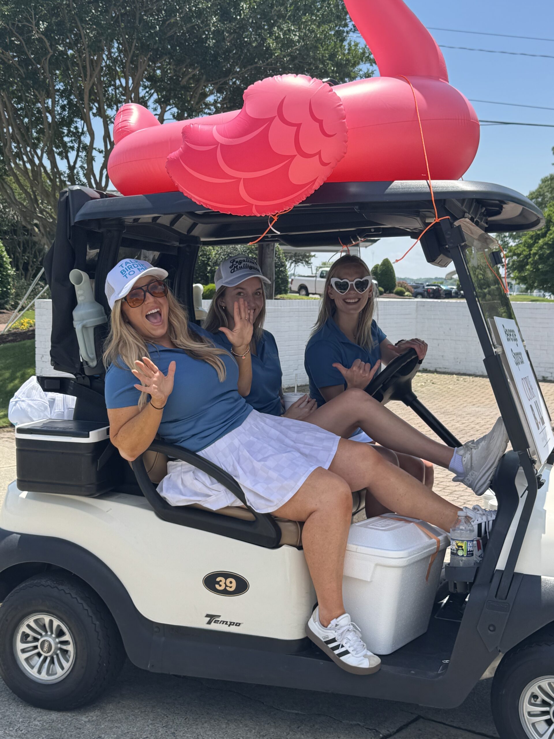 Golfers in a cart decorated with an inflatable flamingo